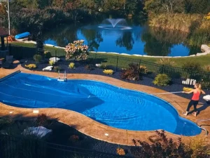 Overhead angle of lady pulling solar blanket across pool
